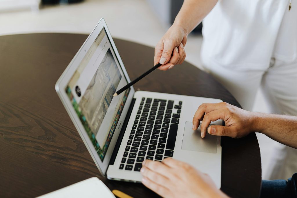 Two people collaborating on a project using a laptop, pointing and planning.